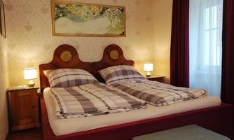 Double bed with separate duvets, wooden headboard, two bedside tables with lamps and large Klimt painting above the bed.