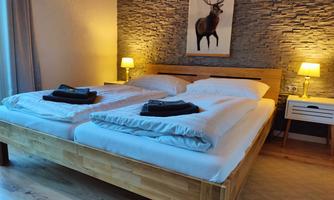 A modern bedroom with a double bed and cozy lighting. A picture of a deer hangs on the wall.