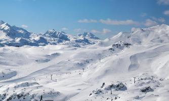 An impressive snow landscape with high mountains and a clear sky. The expanse of the white area invites winter activities.