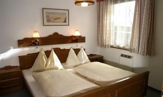 A cozy bedroom with a double bed and two pillows. The room has beautiful curtains and pleasant lighting.