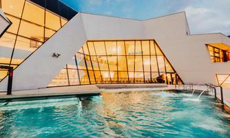 A modern building with large windows and a swimming pool. The surroundings are inviting and stylishly designed.
