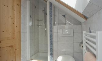 A modern bathroom with a skylight and bright tiles. There is a shower, a toilet, and a towel warmer.