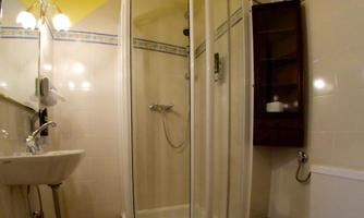 A small bathroom with a shower, a sink, and a toilet. The walls are light and the ceiling is painted yellow.