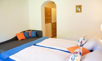 An inviting bedroom with two beds and colorful pillows. The walls are light, and the room feels friendly and bright.