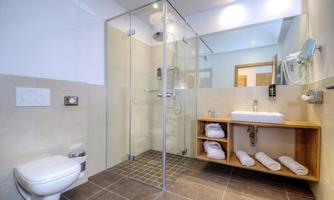 A modern bathroom with a glass shower and a stylish sink unit. Soft towels are neatly stacked and the design is bright and inviting.