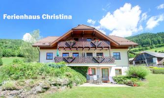 A beautiful holiday home with several balconies and a green surrounding. In the background, hills and a blue sky can be seen.