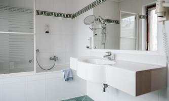 A modern bathroom with a bathtub and a shower. The walls are light tiled, and the sink area is elegantly designed.
