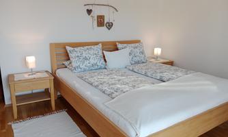 A cozy bedroom with a wooden bed and soft pillows. Gentle light from the nightstands creates an inviting atmosphere.