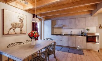 A modern kitchen with a dining area. The room is bright and friendly, with wooden ceilings and a decorative wall painting.