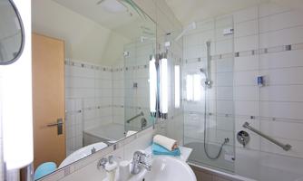 A modern bathroom with a shower and a bathtub. The space is bright and clean, featuring a large mirror and elegant fixtures.