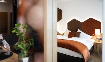 A modern bedroom with a large bed and elegant decor. The warm colors create an inviting atmosphere.