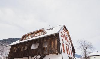 A charming building in alpine style, partially clad in wood. It is located in a picturesque, snow-covered setting.
