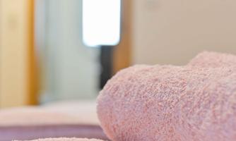 Two clean, pink towels lie on a table. In the background, a bright room with a door and a window is visible.