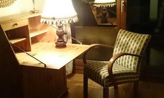 A cozy room with a wooden desk and a chair. Two lamps provide warm light and a pleasant atmosphere.