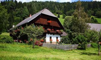 A traditional farmhouse surrounded by green meadows and trees. Flowers adorn the windows, and the landscape is idyllic.