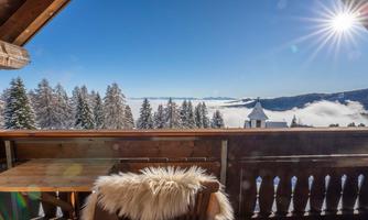 A beautiful view from a terrace of snowy mountains and forests. The sky is clear and sunny, with clouds in the valley.