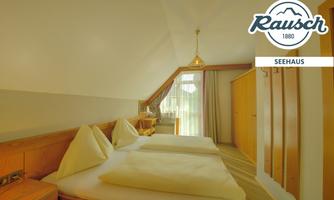 A cozy bedroom with two single beds and light wood decor. Large windows provide plenty of natural light.