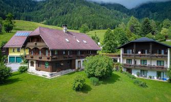 A charming building set amidst green meadows and mountains. The complex consists of several buildings with balconies and an inviting garden.