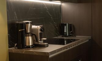 A modern kitchen with an elegant black marble backsplash. Various kitchen appliances, including a coffee machine and a kettle, are well arranged.