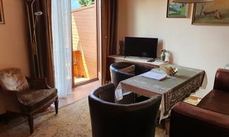A cozy living space with a table and chairs. In the background, there is a window with access to a small balcony.