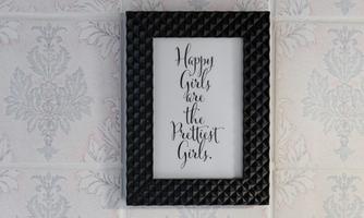 A framed quote on a wall. The inscription says: "Happy Girls are the Prettiest Girls."