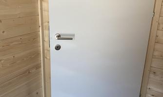 A white door in a wooden room. The floor is tiled.