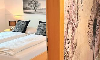 A cozy bedroom with a double bed and elegant decoration. The wall is adorned with an appealing pattern.
