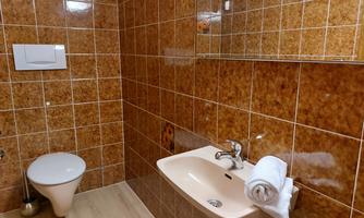 A simple bathroom with brown tiles and a sink. On the sink lies a clean towel.