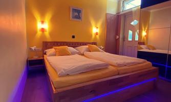 A cozy bedroom with a large wooden bed and yellow walls. Warm lighting and modern details create a relaxed atmosphere.