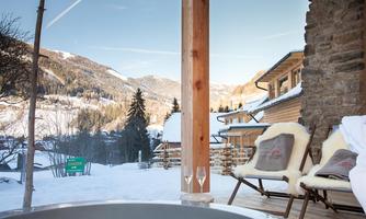A relaxing view of snow-covered mountains from a terrace. Two glasses are on a table to enjoy the cozy atmosphere.