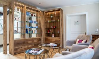An elegant room with modern furniture and a wooden shelf. Various products are visible on the shelf, including personal care items.
