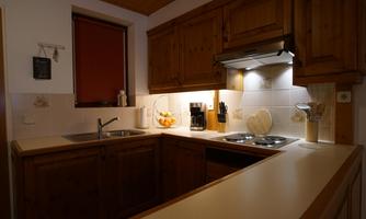 A cozy kitchen with wooden cabinets and modern appliances. The countertop is tidy and well-lit.