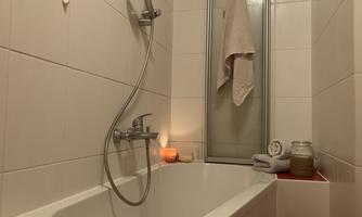 A modern bathroom with a bathtub and a shower. Soft lighting and toiletries create a relaxed atmosphere.
