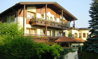 A beautiful house in rural style with several balconies. Surrounded by lush greenery and trees.