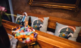 A wooden bench with decorative cushions featuring a parrot in a marine look. In the foreground, colorful candies are visible.