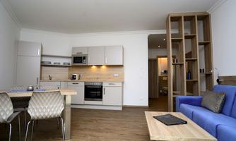 A modern kitchen with bright furniture and a cozy seating area. The room is bright and friendly furnished.