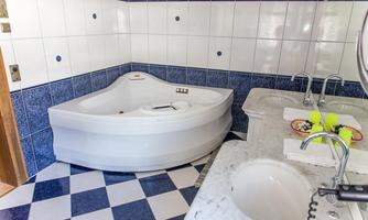 A modern bathroom with a white whirlpool bathtub and blue and white tiles. There is also a marble vanity top with a sink.