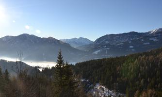 An impressive mountain landscape with green forests and snow-capped peaks. The clear sky allows the natural beauty of the surroundings to shine.