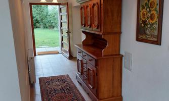 An inviting hallway with a wooden cabinet and an Oriental rug. The door leads outside to the garden.