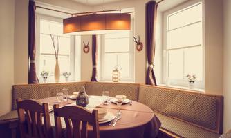 An inviting dining room with a round table and cozy benches. The windows let in plenty of light and create a bright atmosphere.