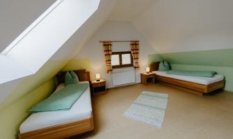 A bright bedroom with two single beds and a cozy atmosphere. Large windows provide plenty of daylight and the walls are painted in soft shades of green.