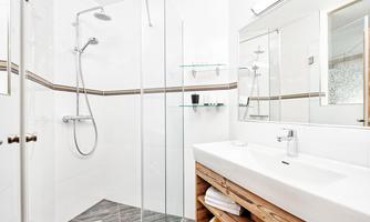 A modern bathroom with a glass shower enclosure and an elegant vanity. The walls are bright and clean, creating a fresh atmosphere.