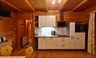A modern kitchen with a wooden ceiling and bright furnishings. The kitchen is well-equipped and has a cozy atmosphere.