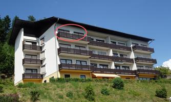 A modern building with several balconies in a green environment. The facade is bright and friendly designed.