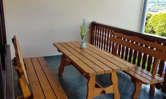 A cozy balcony with a wooden table and benches. In the center, there is a vase with fresh flowers.