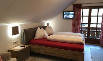A cozy room with a double bed and modern amenities. The room has windows with a view outside and a pleasant atmosphere.