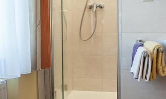 A modern bathroom with a glass shower. Fresh towels in various colors are ready.