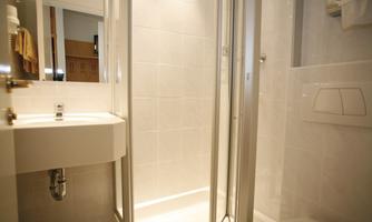 A modern bathroom with a shower and a sink. The walls are brightly tiled and the room feels clean and inviting.