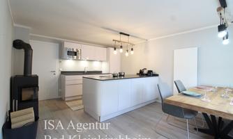Modern kitchen in a bright design with a dining table and a cozy seating area. The amenities include a stove, a microwave, and a wood oven.