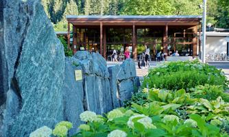 A modern building surrounded by rocks and green plants. In the background, people can be seen enjoying the outdoors.